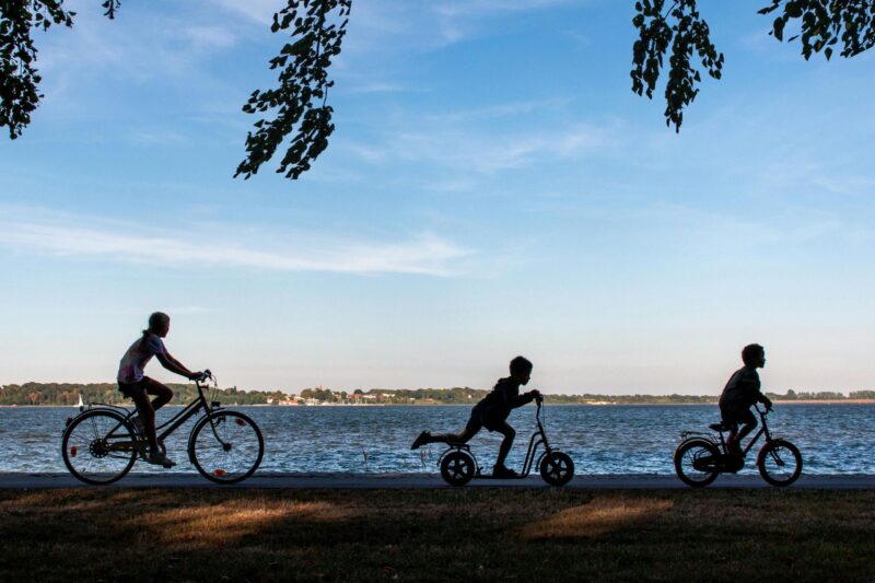 Children Cycling and Scooting by the Lakeside